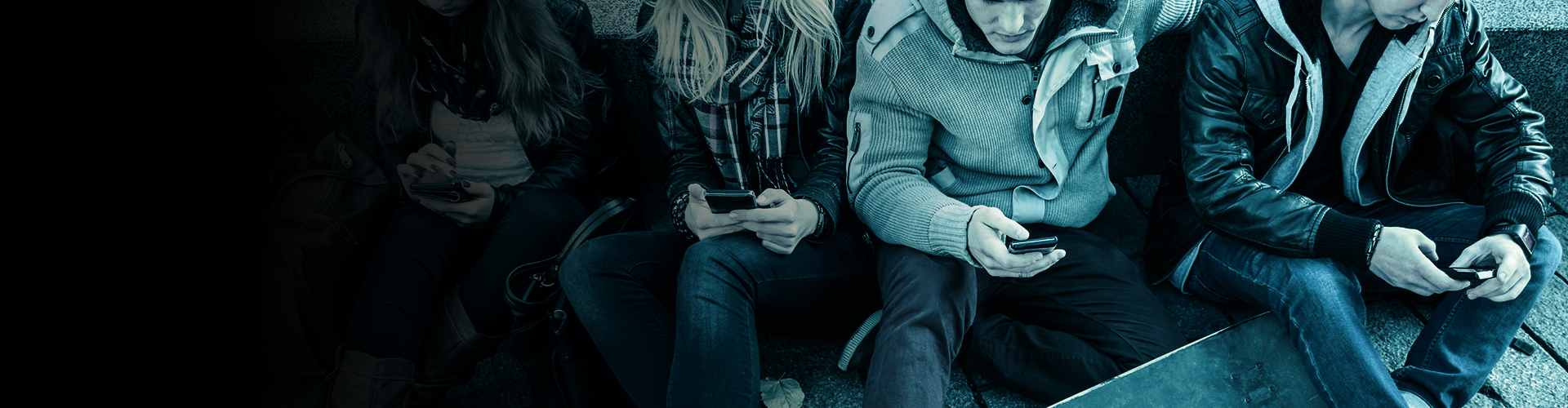 A group of people sitting on the floor looking at mobile phones